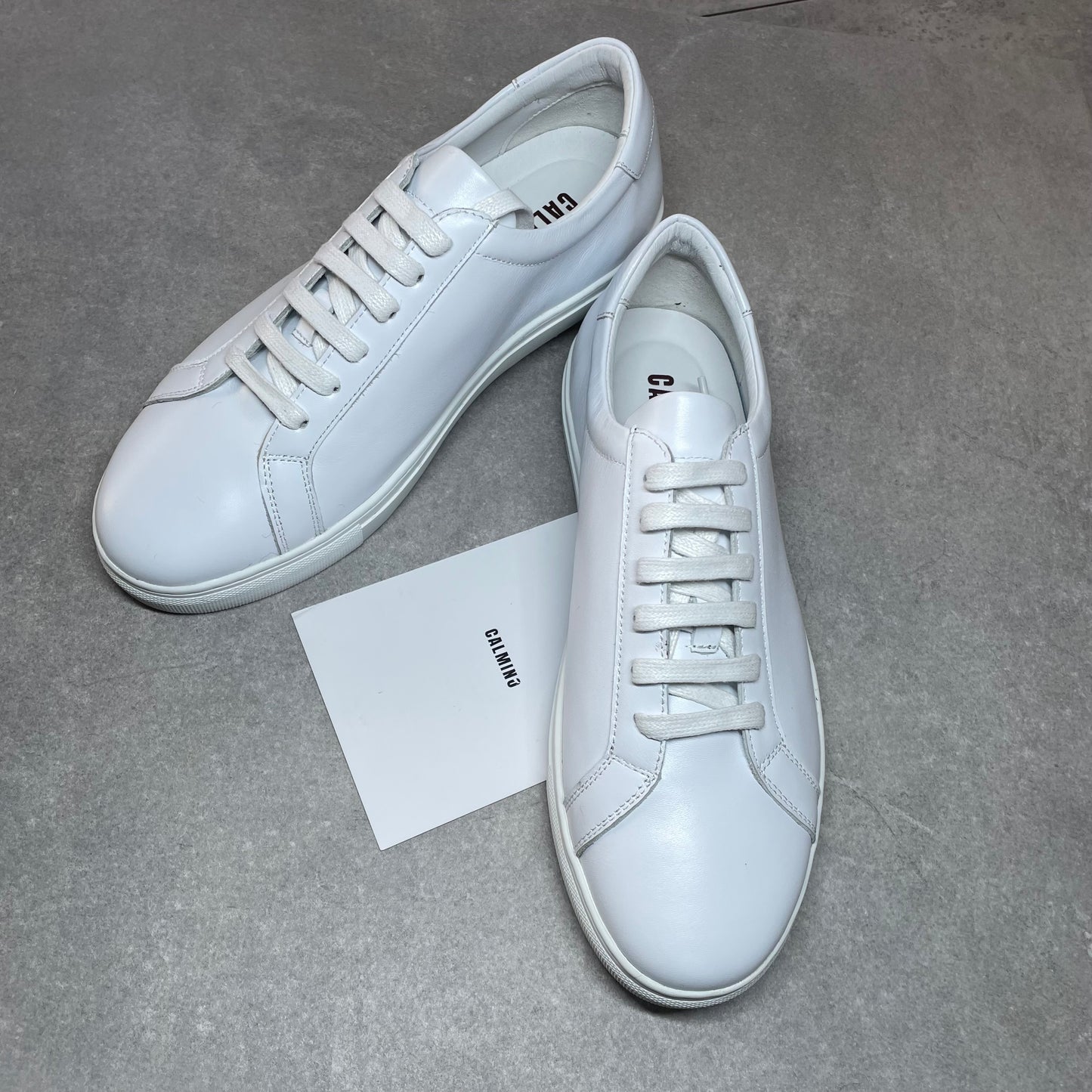 Crafted with premium leather inside and out, the Classic Calmino Leather sneaker delivers exceptional durability and comfort. The timeless white design offers versatile styling options while the quality construction ensures proper foot support and breathability. These sneakers combine traditional craftsmanship with everyday wearability for discerning footwear enthusiasts.