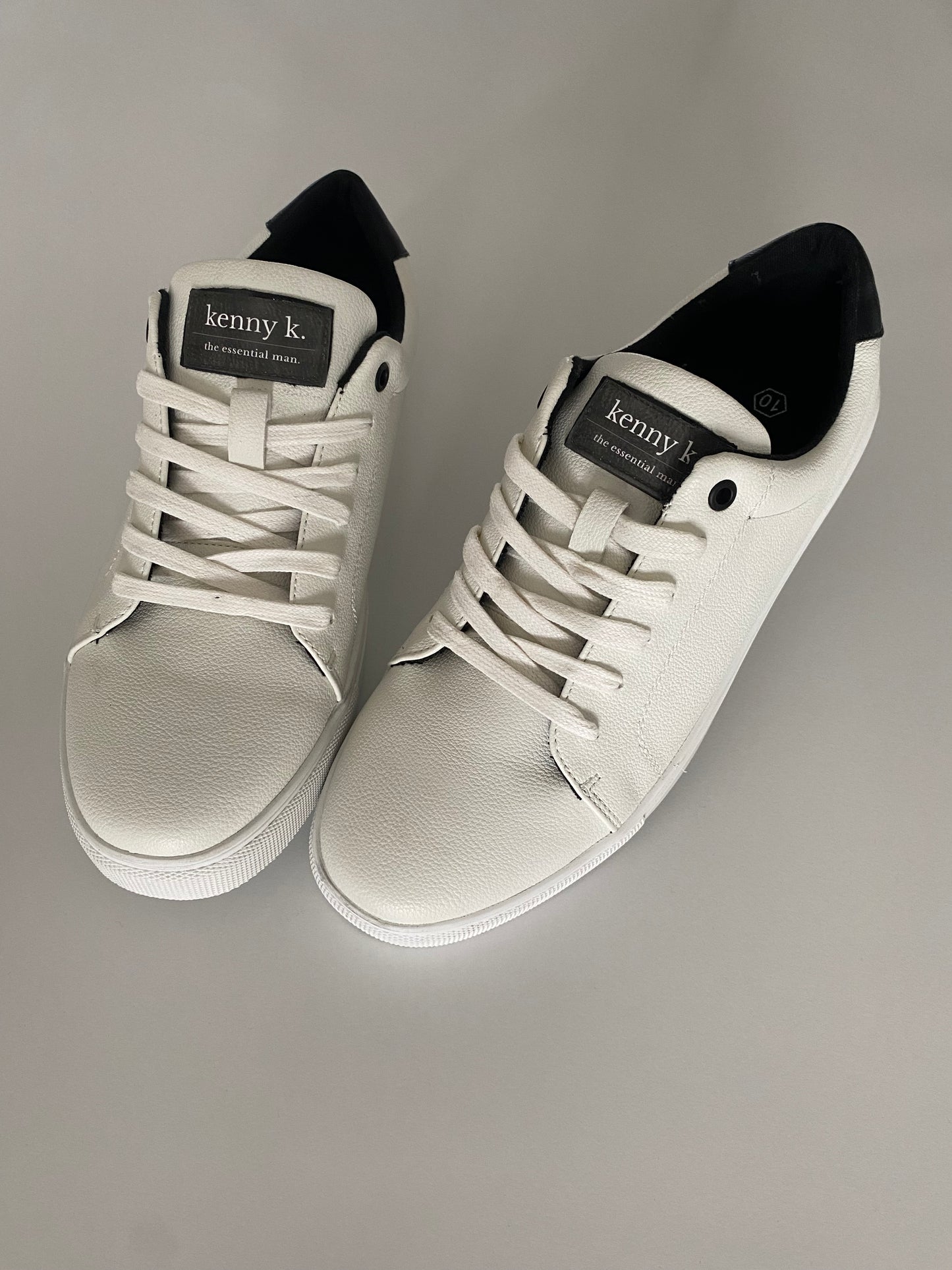 Introducing the essential white sneaker by Connor &amp; Kenny K. Made from high-quality faux leather, these sneakers are stylish and a basic essential for business and leisure. With their classic white design, they are perfect for any outfit and any occasion. Upgrade your footwear game with these must-have sneakers.