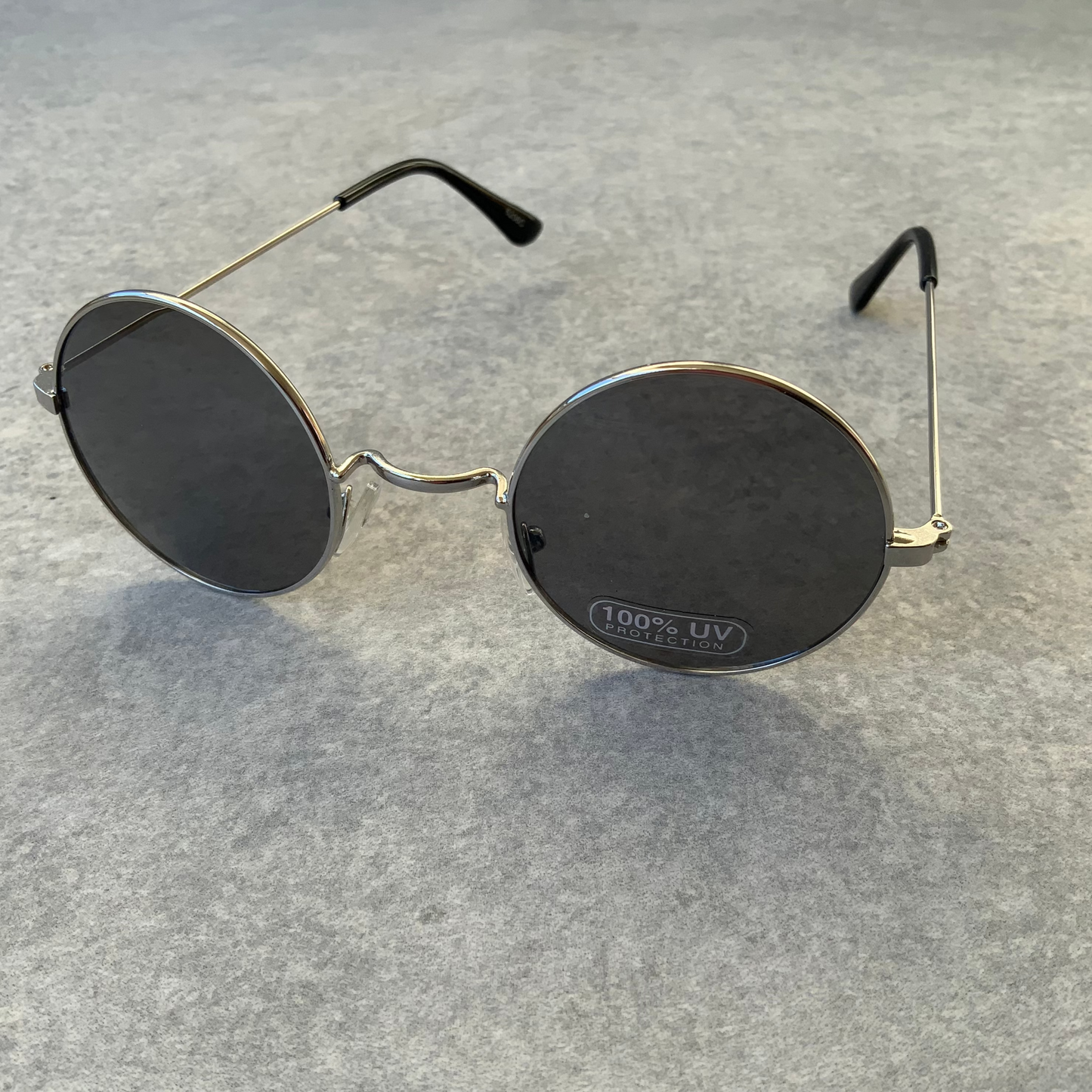 Round John Lennon style sunglasses with black lenses and silver frames.