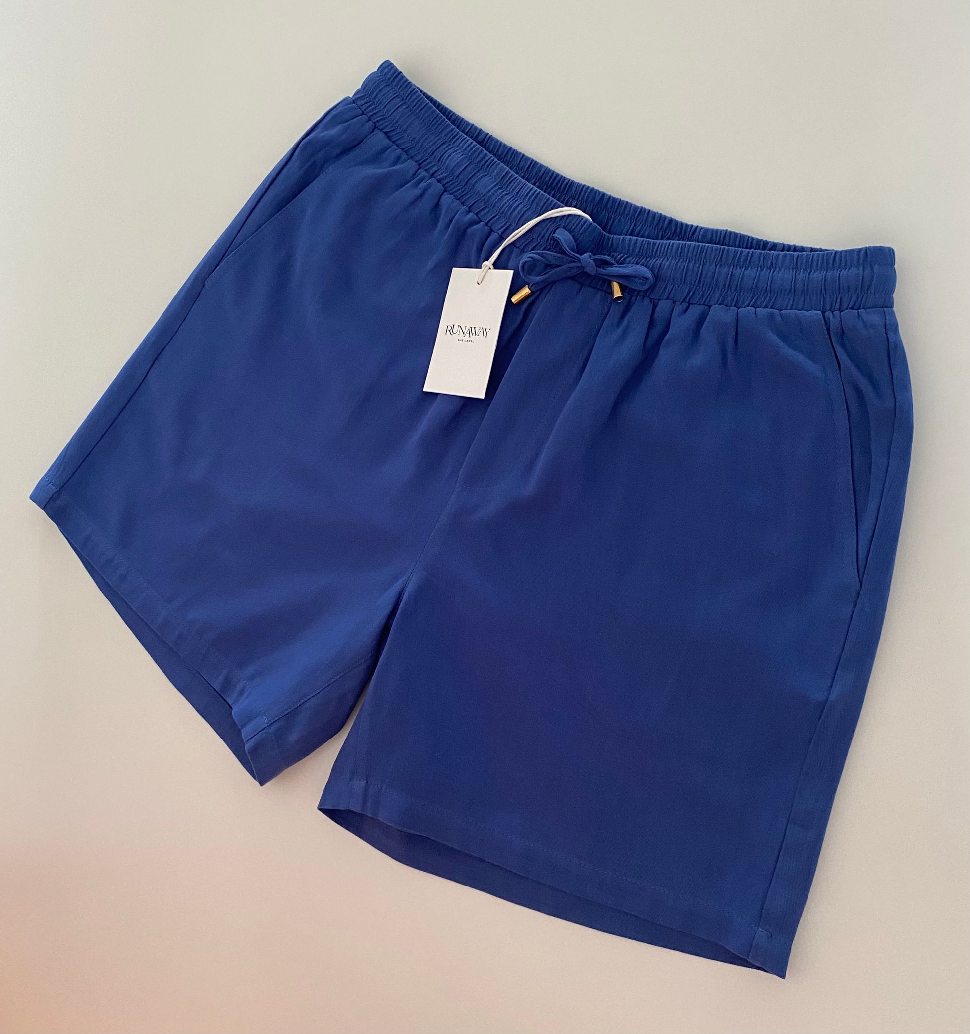 Introducing the RUNAWAY Poolside short, brought to you by kenny k. Made for leisure, these classic shorts are both easy and stylish to wear. Perfect for poolside lounging or any casual occasion.

- Relaxed fit

- Elasticated waistband and pockets

- Side and back pockets

- Lined with no stretch

- 100% cotton

Match this look with a classic AS Colour Tee brought to you by kenny k.&nbsp;